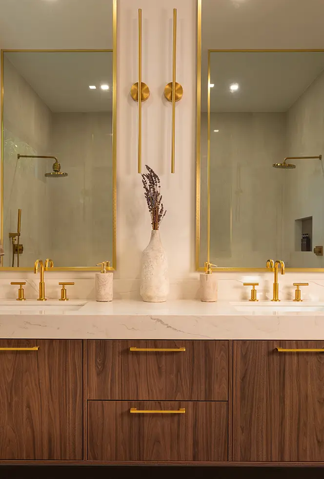 Bathroom vanity in warm wood with brass fittings and a glass walk-in shower