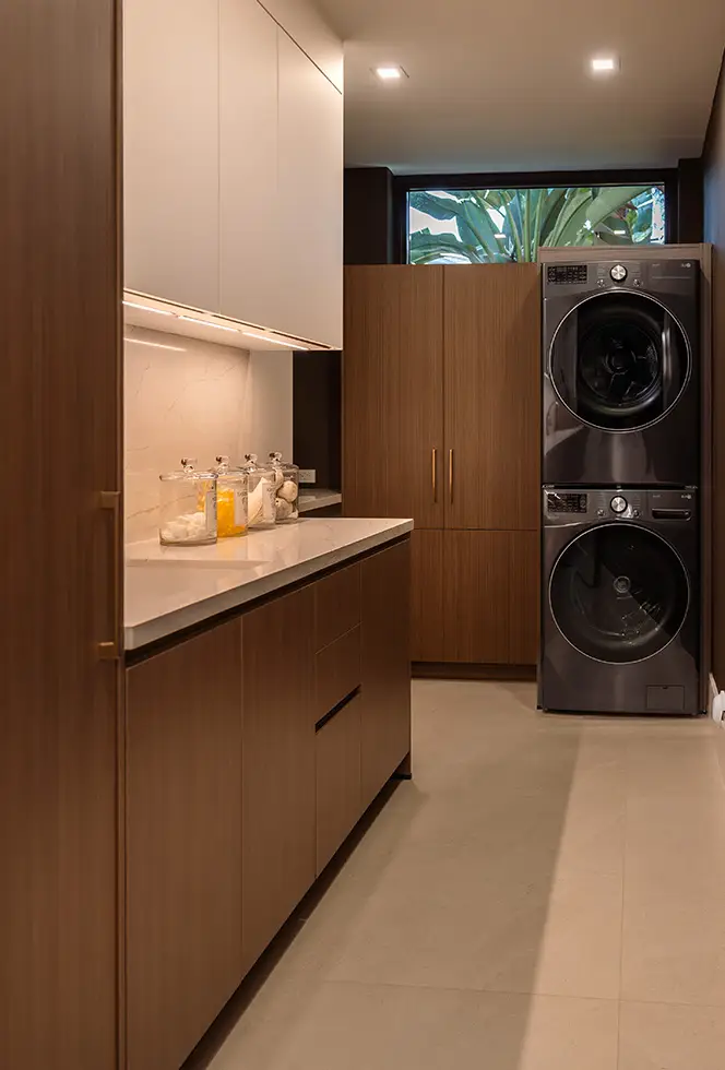 Walnut laundry cabinetry with a stacked washer and dryer and full-height utility storage