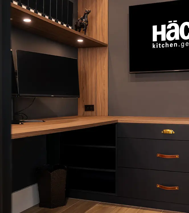 Built-in home office with a wall-mounted screen, oak desktop and dark leather-pull drawers