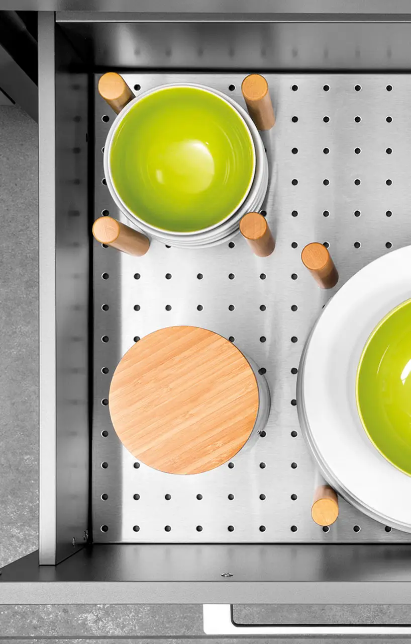 Solid wood plate insert with movable pegs holding bowls and a chopping board in place