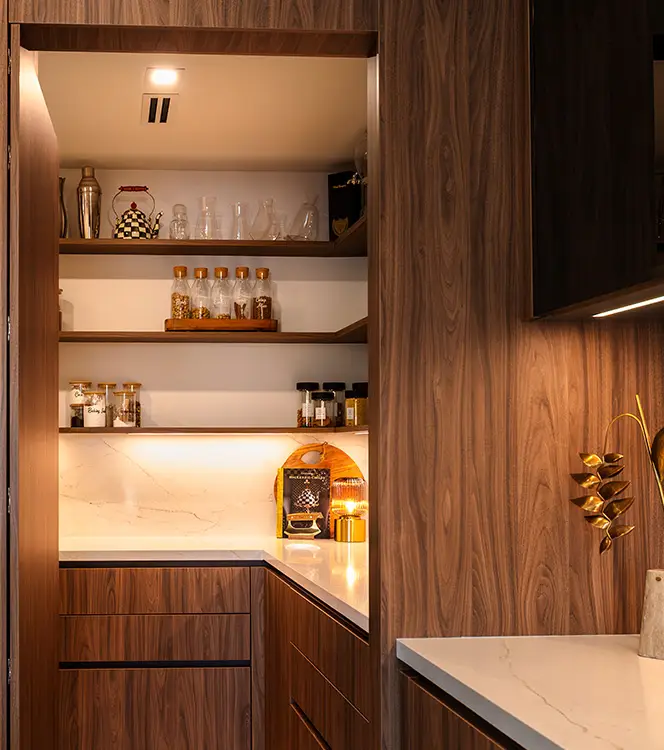 Walk-in pantry in walnut with open shelving, under-shelf lighting and closed base storage